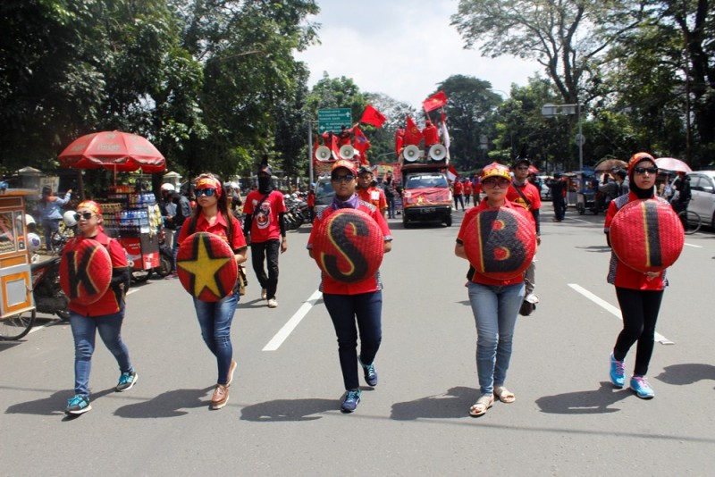Kongres Aliansi Serikat Buruh Indonesia (KASBI) berjalan ke arah Gedung Sate sambil membawa nyiru yang bertuliskan KASBI . (M Taruna Prima Rahardi / JUMPAONLINE)