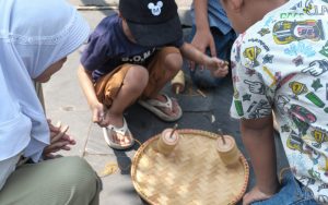 Beberapa pengunjung anak-anak Braga Beken sedang melakukan aktivitas Kaulinan Bah Gembol pada Sabtu, 18 Mei 2024 di depan Rumah Seni Ropih, Braga Panjang.